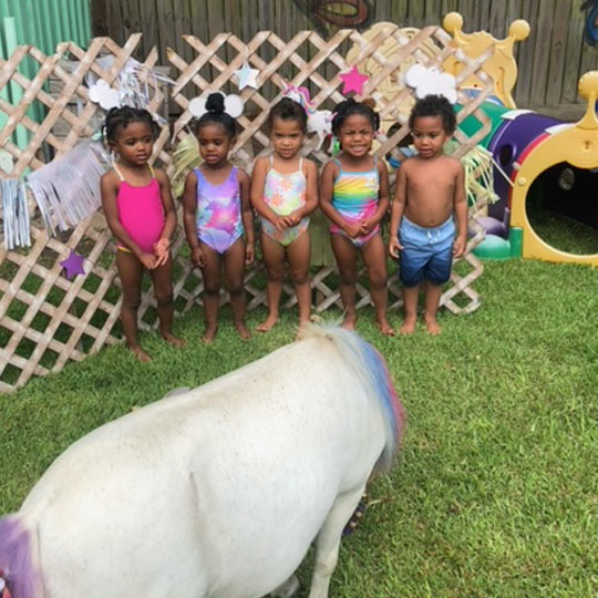 Small children playing with a pony.